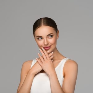 Beautiful skin face woman natural make up healthy skin touching her face. Color background. Gray